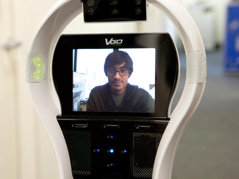 Close-up of the VGo display screen shows a dark haired man in glasses.