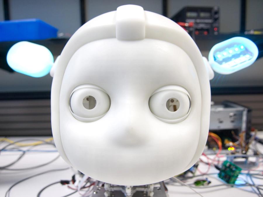 A close up of the robots simple white face and glowing blue ears.