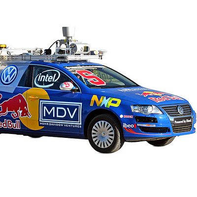 A blue, logo covered self-driving car with a roof rack full of electronics.