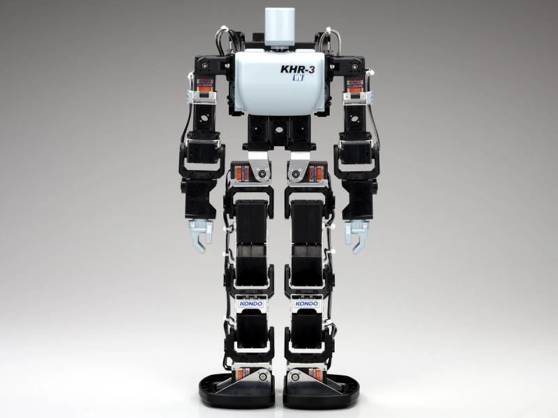 A petite bipedal toy robot with a white torso and head, black arms and legs and gripper hands.