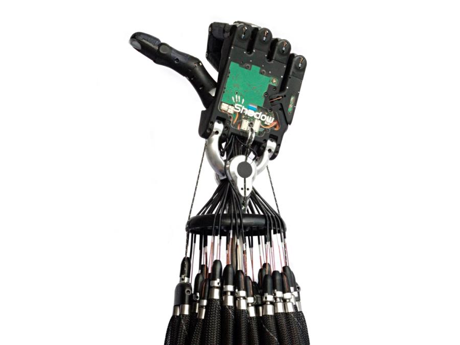 The robotic hand is shown upright with long corded tendons, and with fingers folded and thumb sticking out.