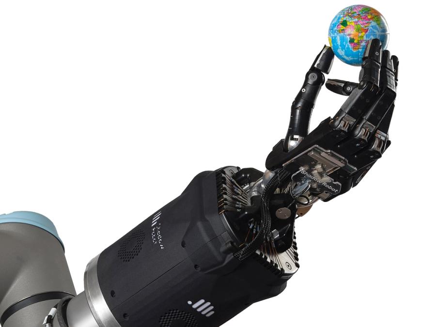 A black prosthetic hand that imitates human fingers and tendons pinches a miniature globe between two fingers.
