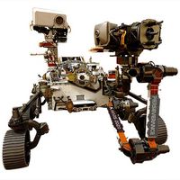 A car-sized rover with tracked wheels, a base covered in scientific equipment, and robotic arms with tools and multiple cameras.