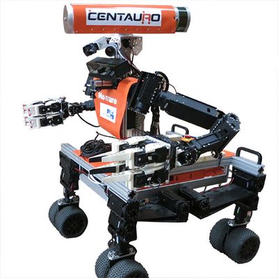 A four-wheeled mobile robot with a wide orange base, orange torso with arms and gripper hands, and a head consisting of electronics and sensors, some of which are exposed and some of which are in an orange horizontal bar.