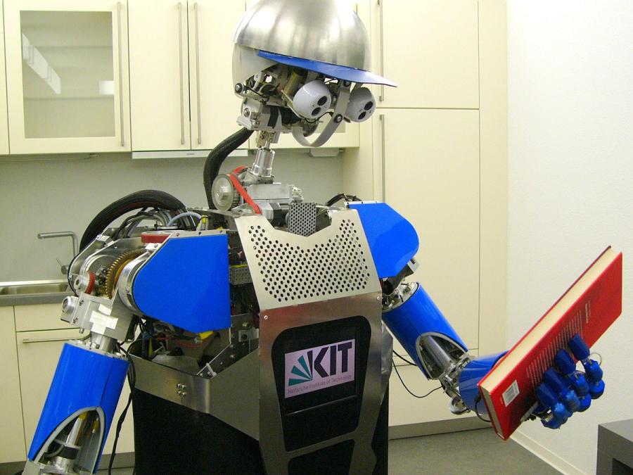 Close up of a humanoid robot looking at a book.
