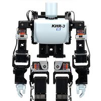 A petite bipedal toy robot with a white torso and head, black arms and legs and gripper hands.