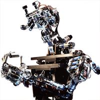 A human shaped robot with exposed electronics looks at it's fingers, which are pushed together to form an O.