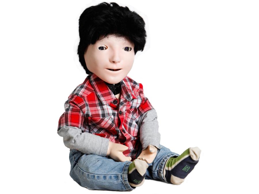 A child-size humanoid robot that is meant to look like a young boy in jeans, socks, a plaid shirt and blue hat.