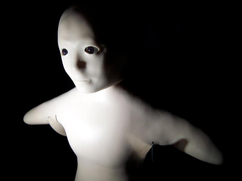 Close-up of a humanoid robot the size of small child, with a soft torso with a bald head, a doll-like face, and stumps in place of limbs.