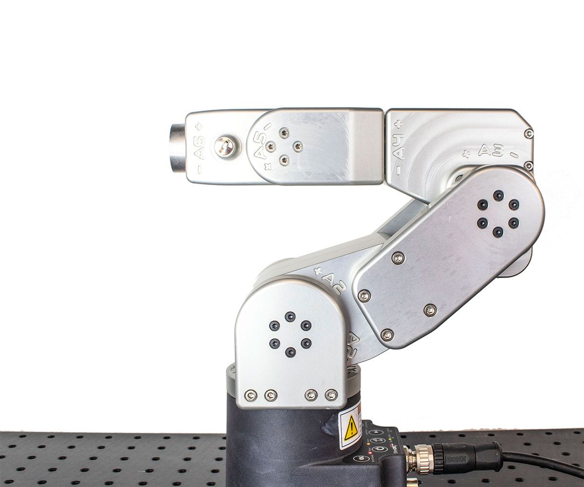 A compact, 33cm tabletop silver robotic arm moves it's end effector towards the camera and then back.