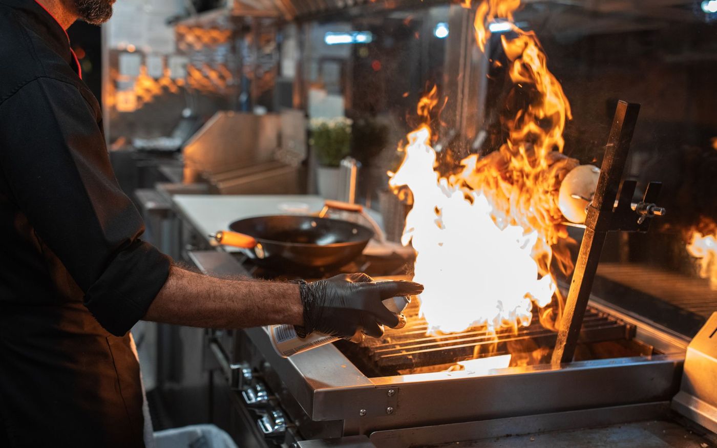 Gestor de restaurante observa a operação da cozinha enquanto consulta informações em um tablet. — Foto: RDNE Stock project (Pexels)