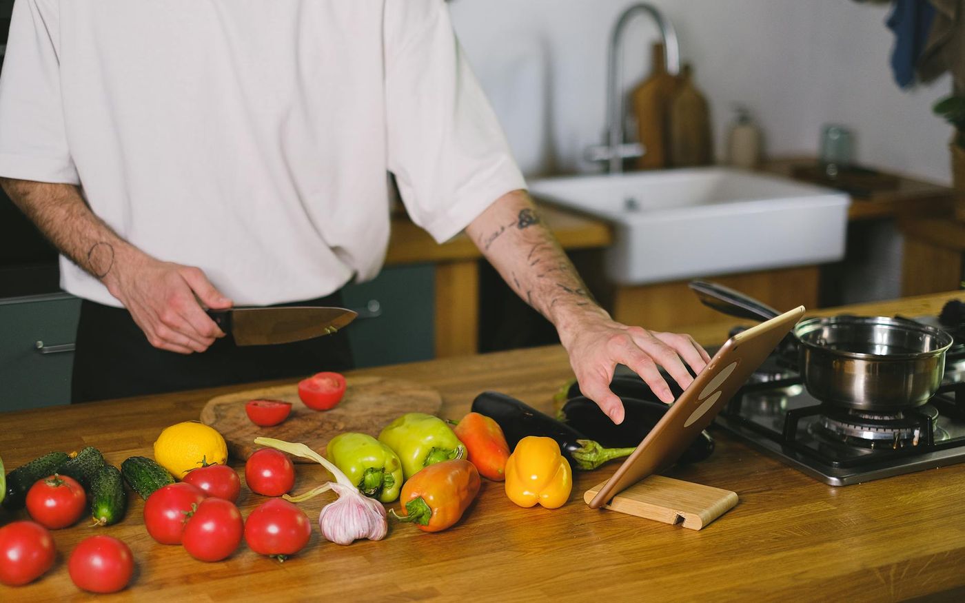 Chef analisando dados de cardápio em tablet em cozinha profissional com ingredientes frescos ao fundo — Foto: Anna Shvets (Pexels)