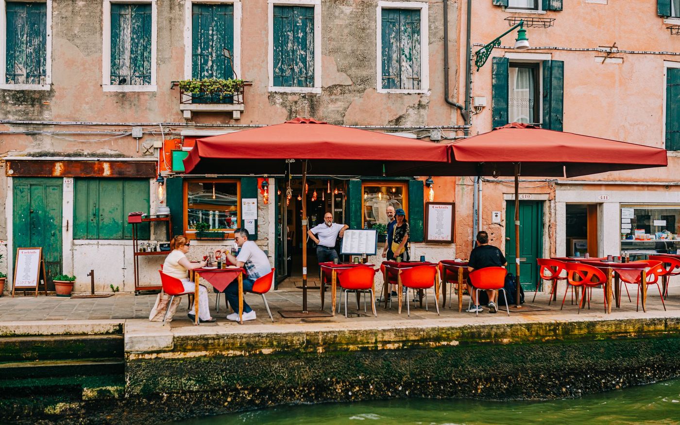 Clientes almoçam em um restaurante frequentado por turistas enquanto o gestor acompanha a operação. — Foto: Helena Jankovičová Kováčová (Pexels)