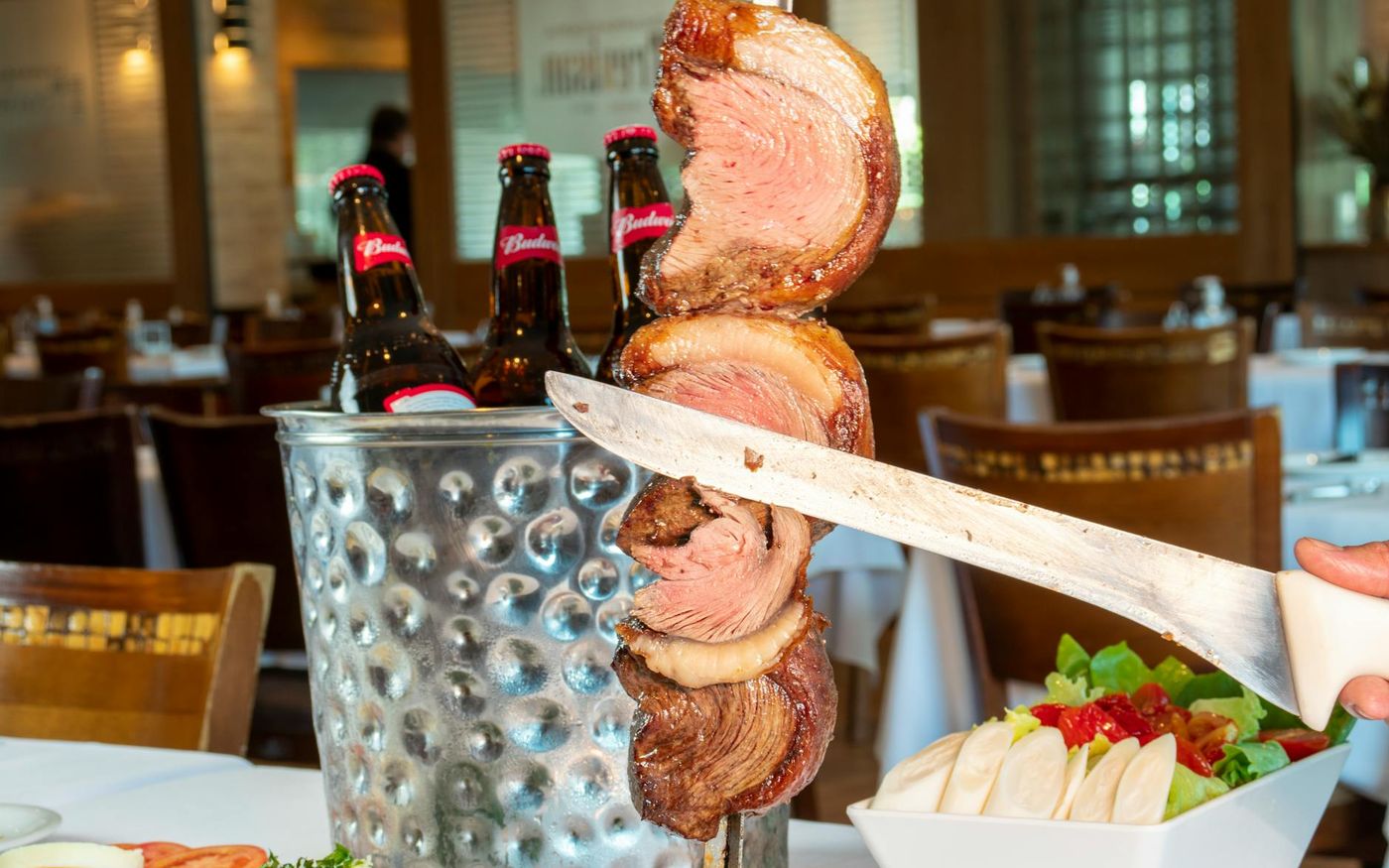 Restaurante brasileiro lotado à noite, com garçons servindo pratos e clientes animados, representando o crescimento de 3,4% nas vendas em abril.