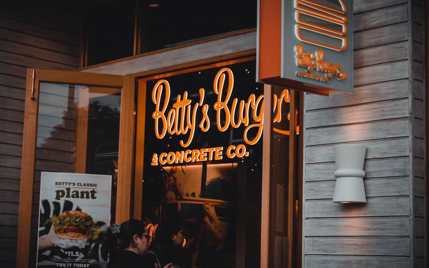 Interior de uma hamburgueria contemporânea em São Paulo, com equipe preparando pedidos e clientes no salão. — Foto: Nenyasha Manzvera (Pexels)