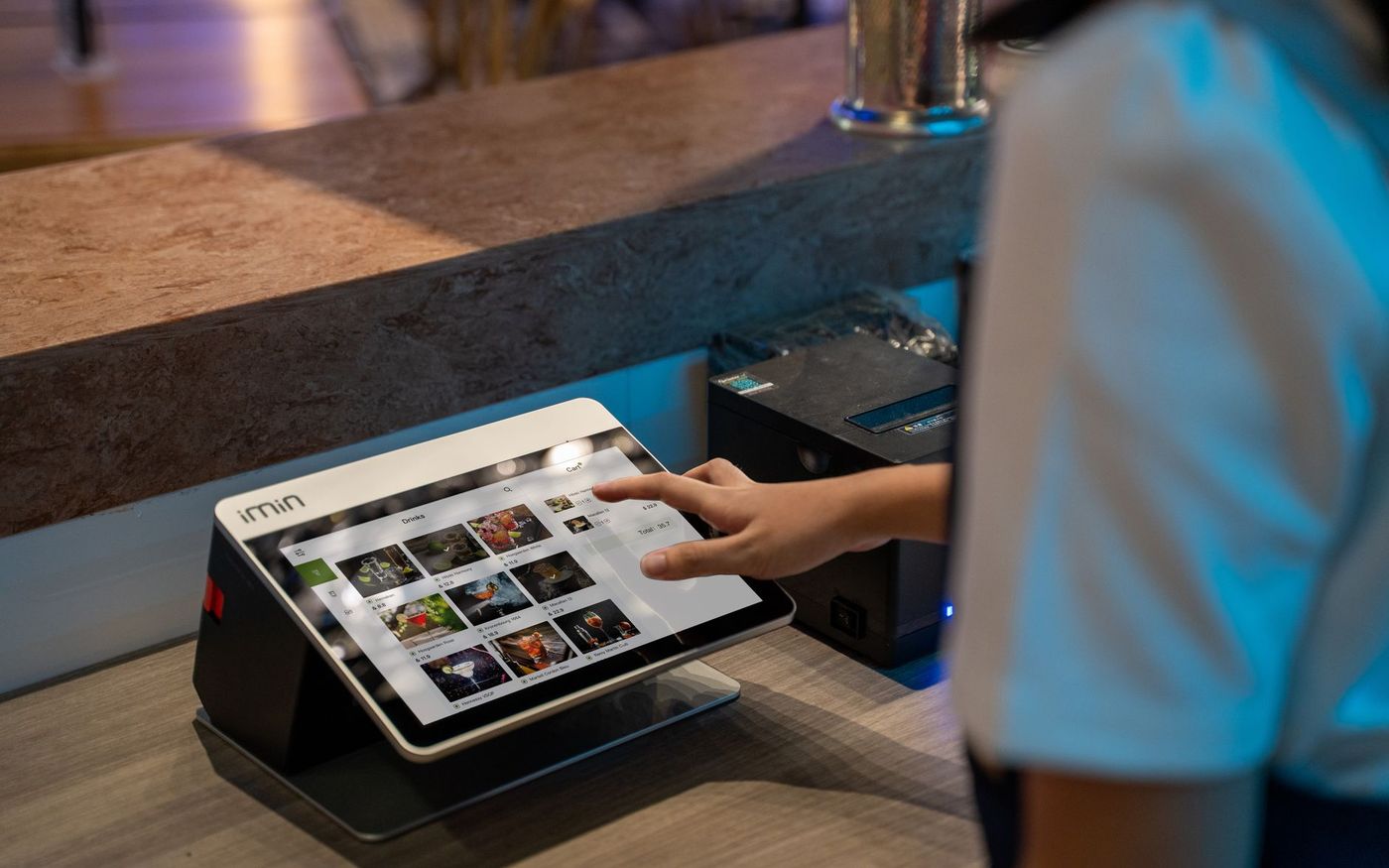 Gestor de restaurante consulta um tablet durante a operação, com a equipe trabalhando ao fundo. — Foto: iMin Technology (Pexels)
