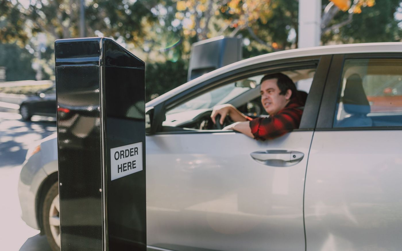 Cliente em um drive-thru recebe ajuda de uma funcionária diante de um terminal digital de pedidos. — Foto: RDNE Stock project (Pexels)