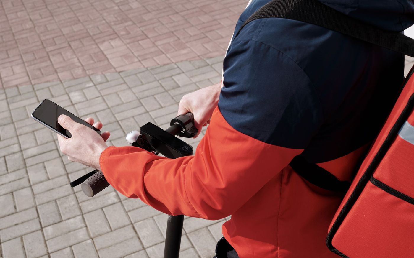 Entregador de moto parado diante de um restaurante, com funcionários visíveis na entrada. — Foto: Norma Mortenson (Pexels)