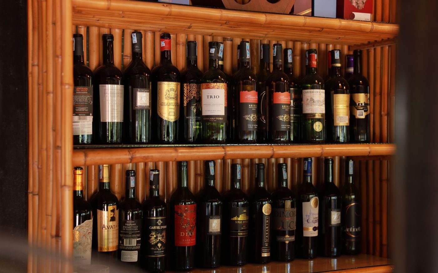 Gestor de restaurante analisa uma carta de vinhos ao lado de garrafas expostas. — Foto: HONG SON (Pexels)