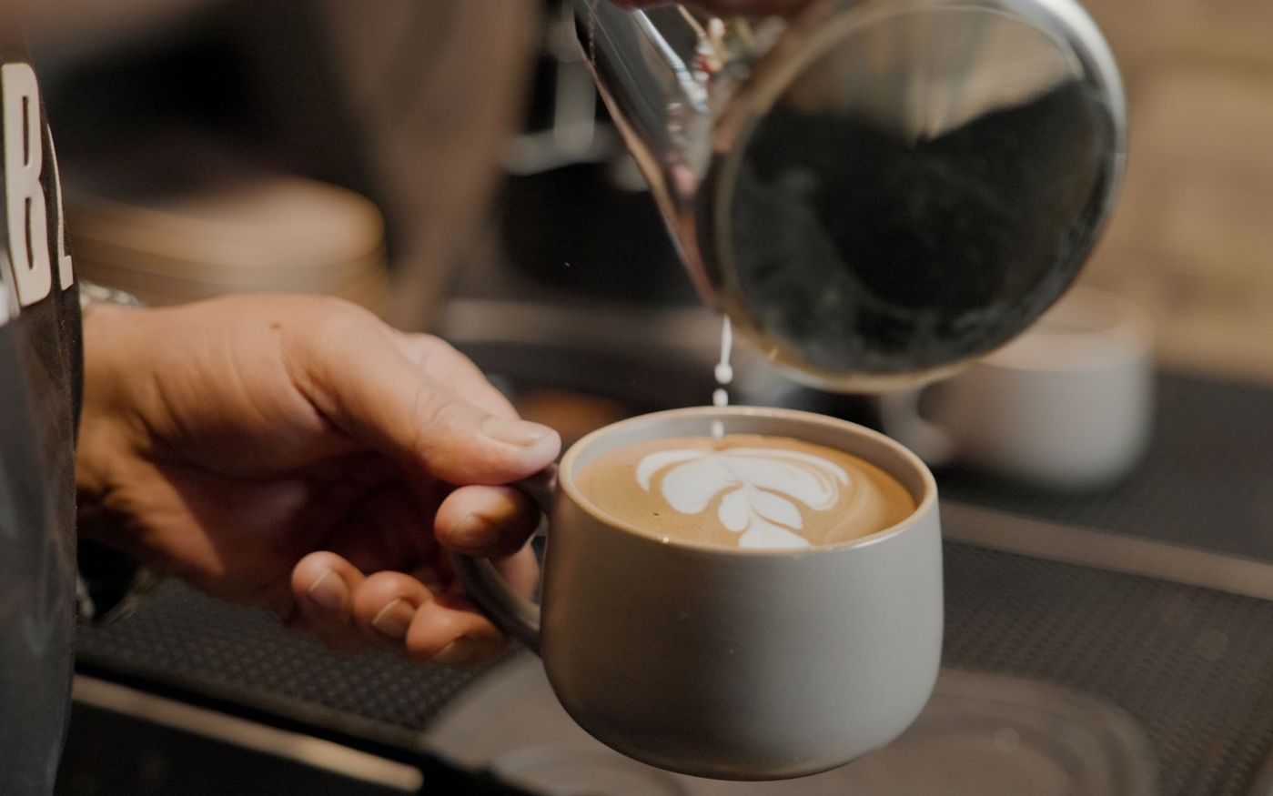 Barista prepara café em uma cafeteria enquanto a equipe confere os grãos e os padrões de preparo. — Foto: Mustafa Fatemi (Pexels)