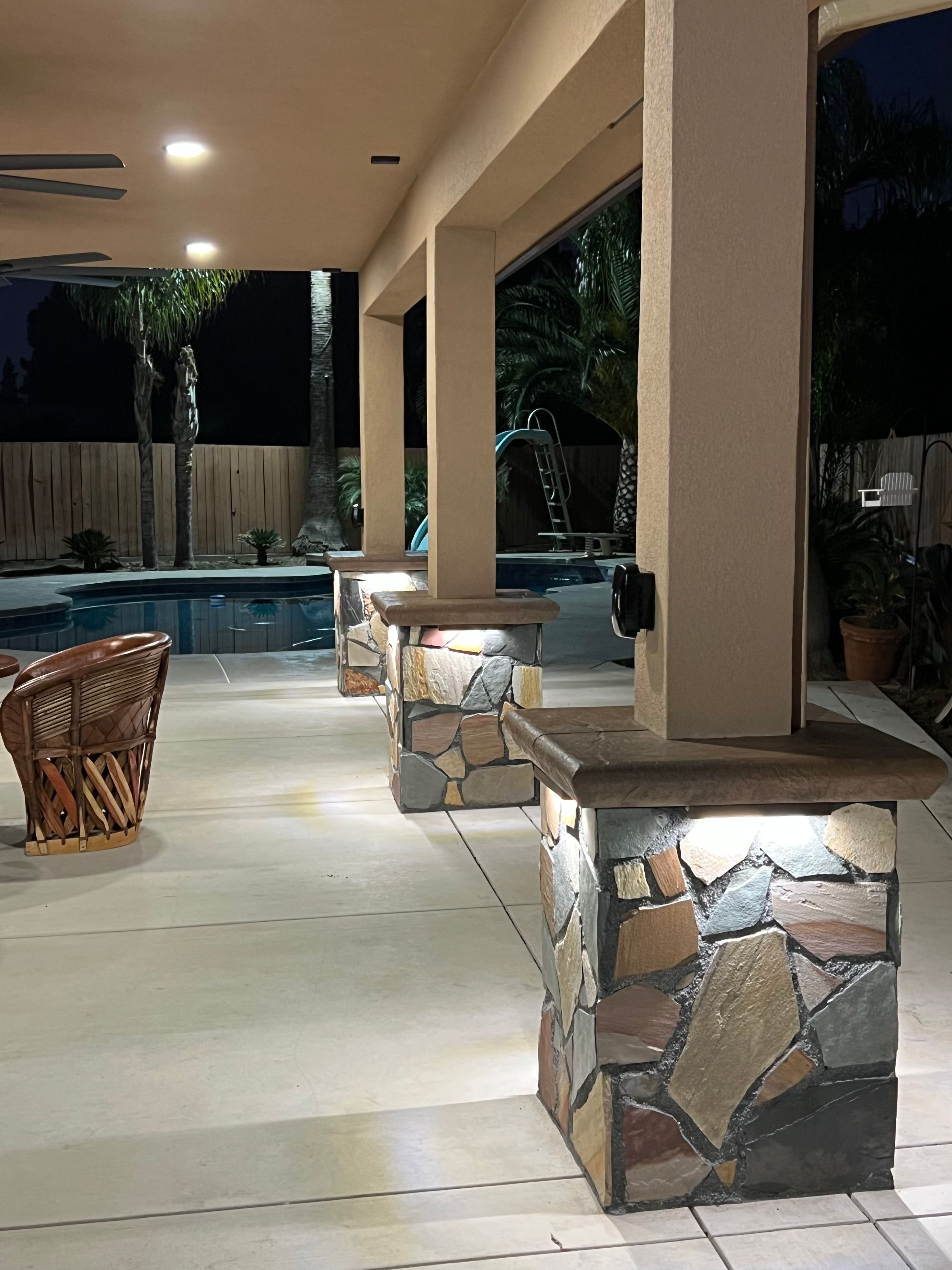 Covered patio with lit stone pillars