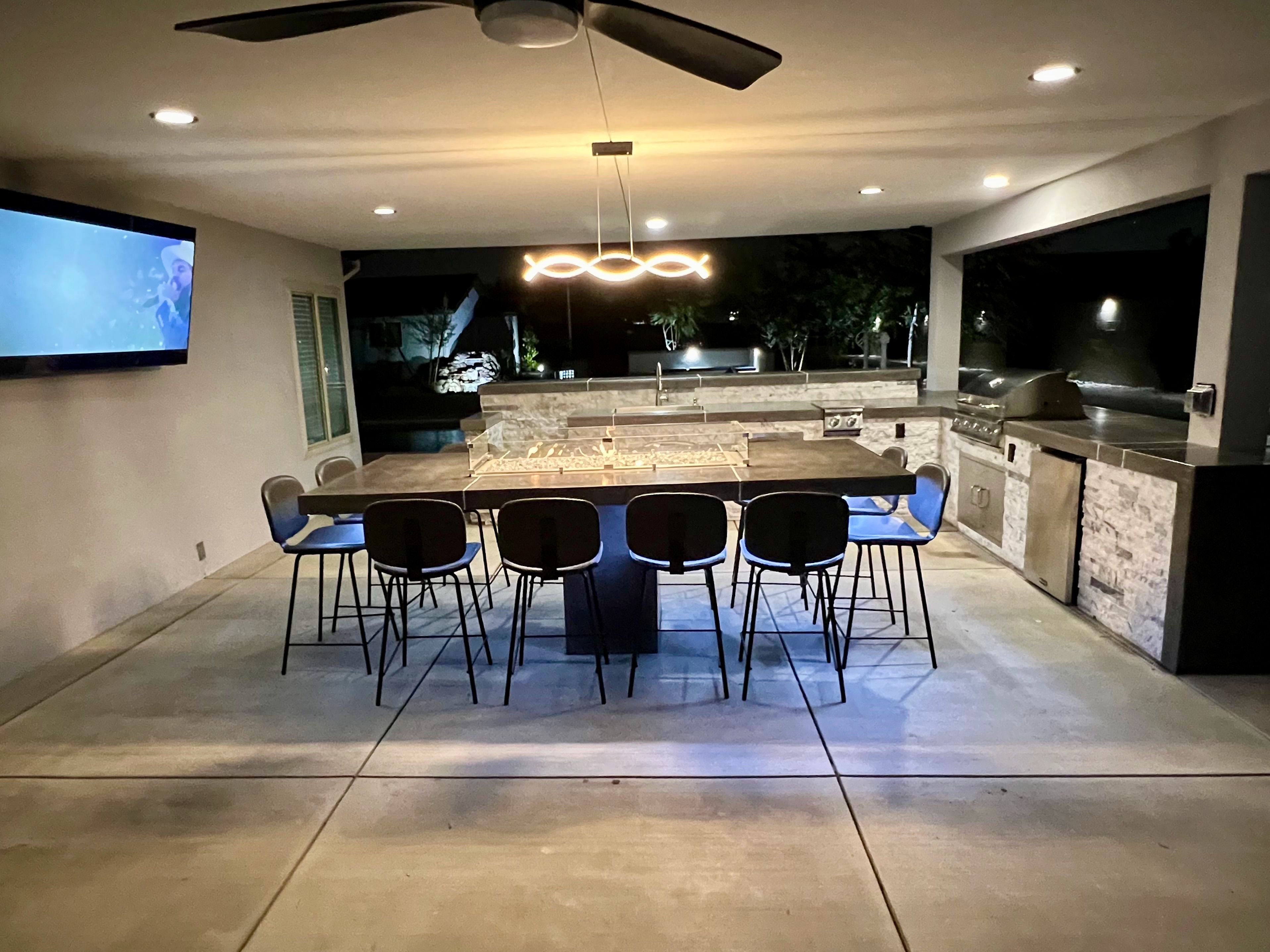 Luxury covered patio with fire pit table and outdoor kitchen at night