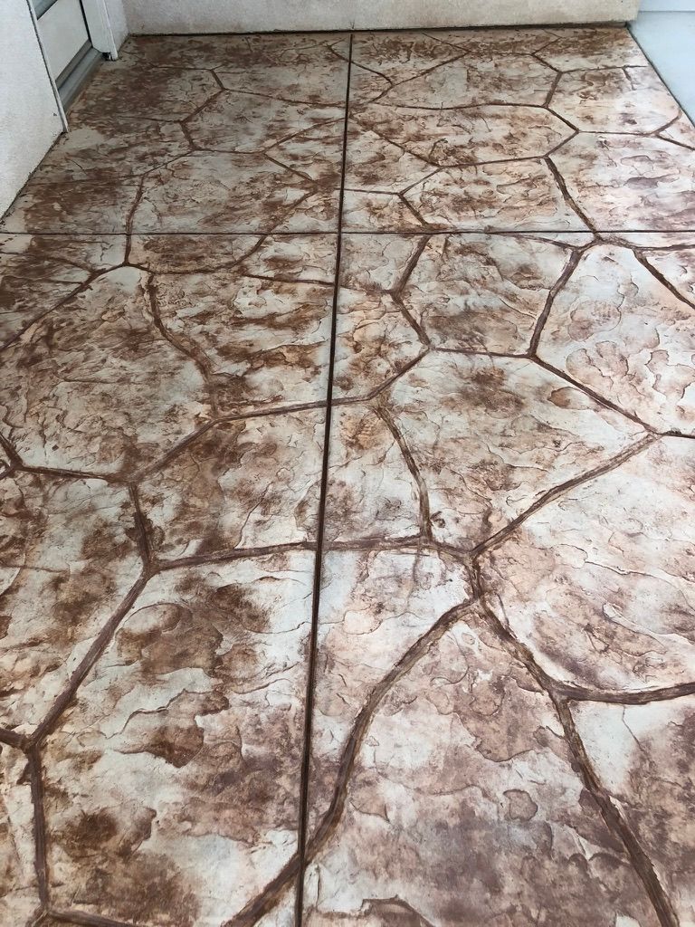 Covered porch flooring featuring flagstone pattern stamped concrete in warm earth tones with natural stone appearance