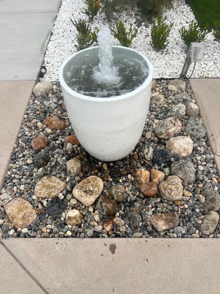 White pot fountain with mixed river rocks