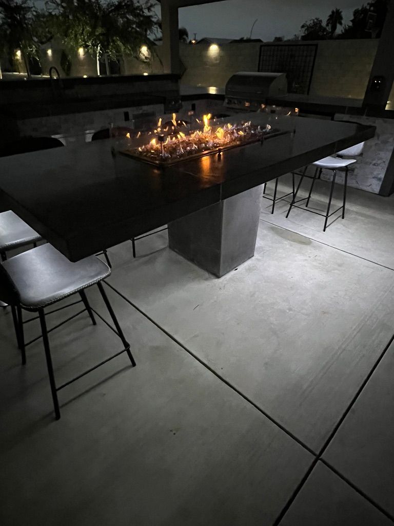 Fire pit table with outdoor kitchen at night