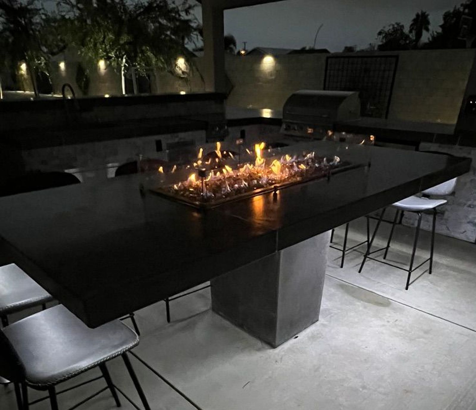 Fire pit table with outdoor kitchen at night