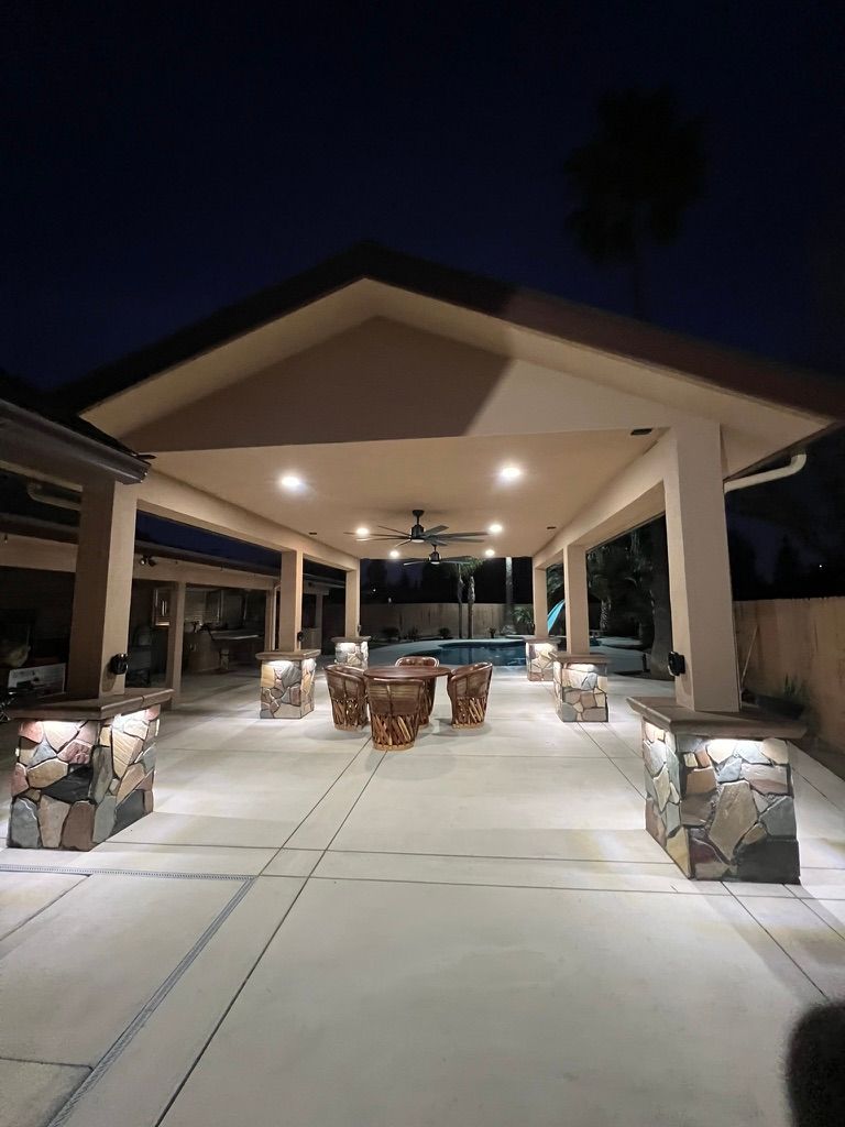 Covered patio with stone pillars and pool view at night