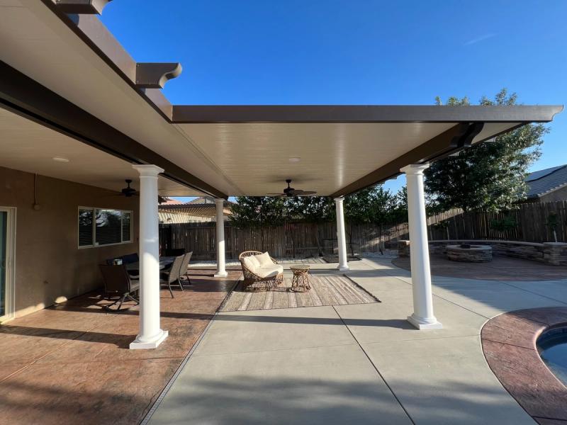 Custom covered patio featuring white support columns, ceiling fans, and decorative stamped concrete