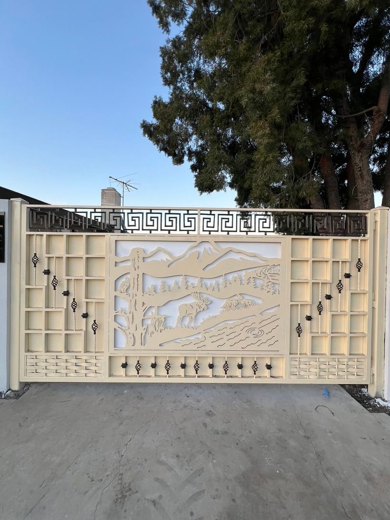 Large decorative metal gate featuring custom laser-cut mountain and wildlife scene with Greek key pattern railing above