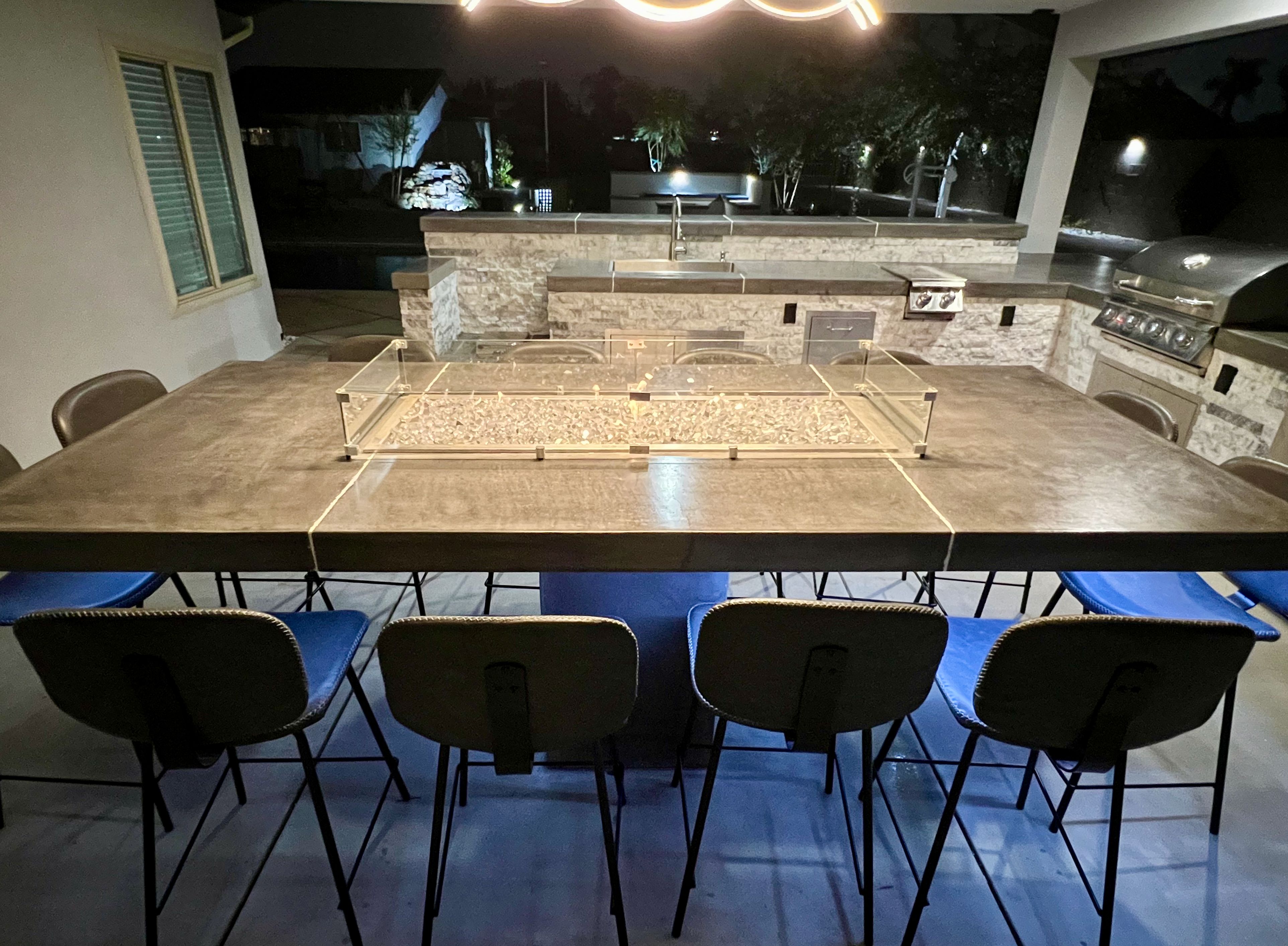 Luxury outdoor kitchen with fire pit table and ambient lighting