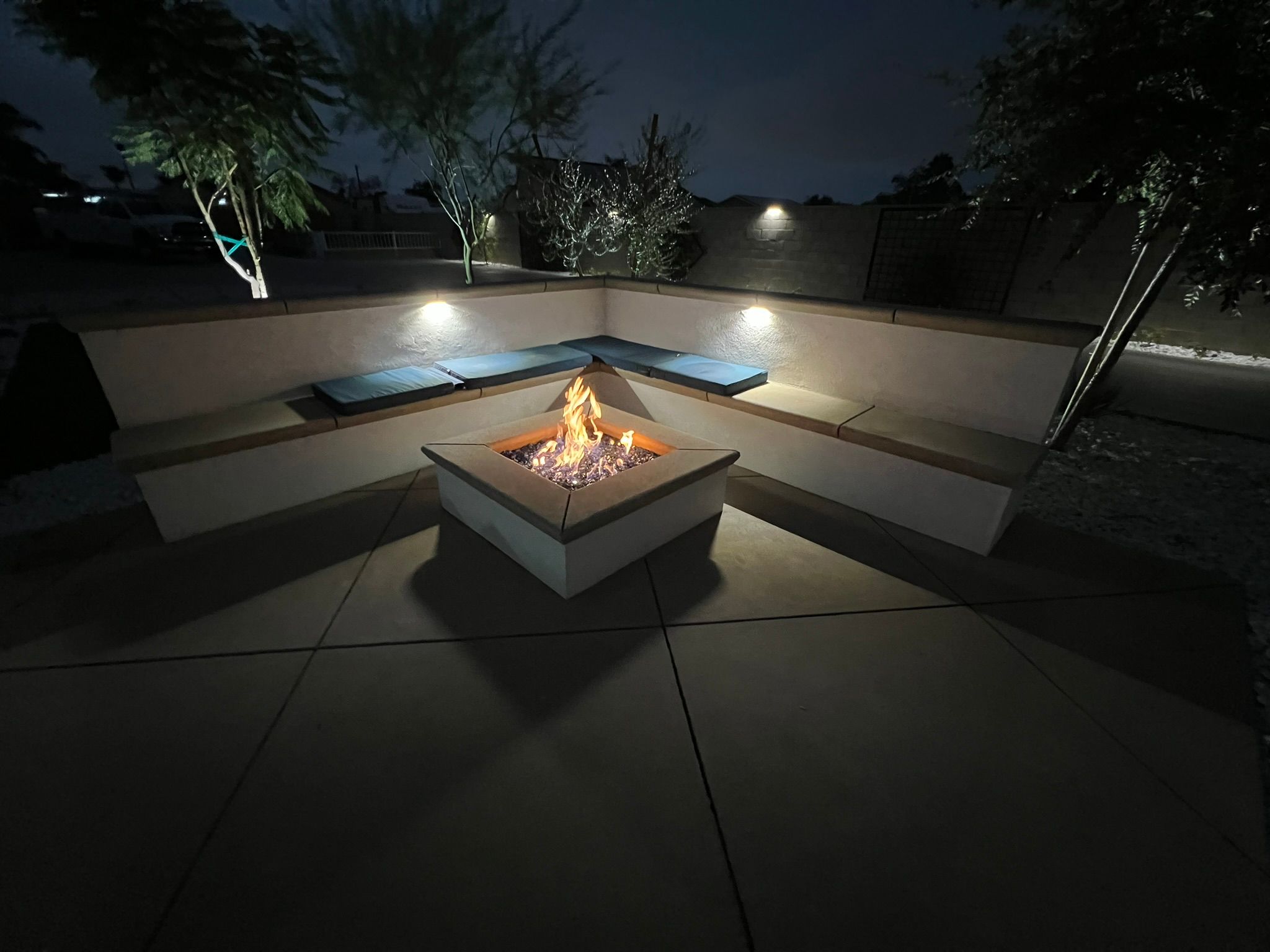 Square fire pit with built-in bench seating at night