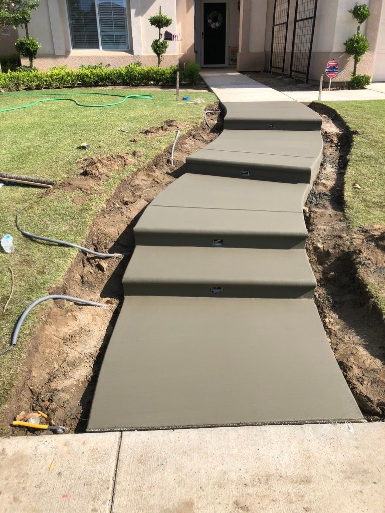 Newly poured concrete walkway and steps with smooth broom finish leading from driveway to front entry