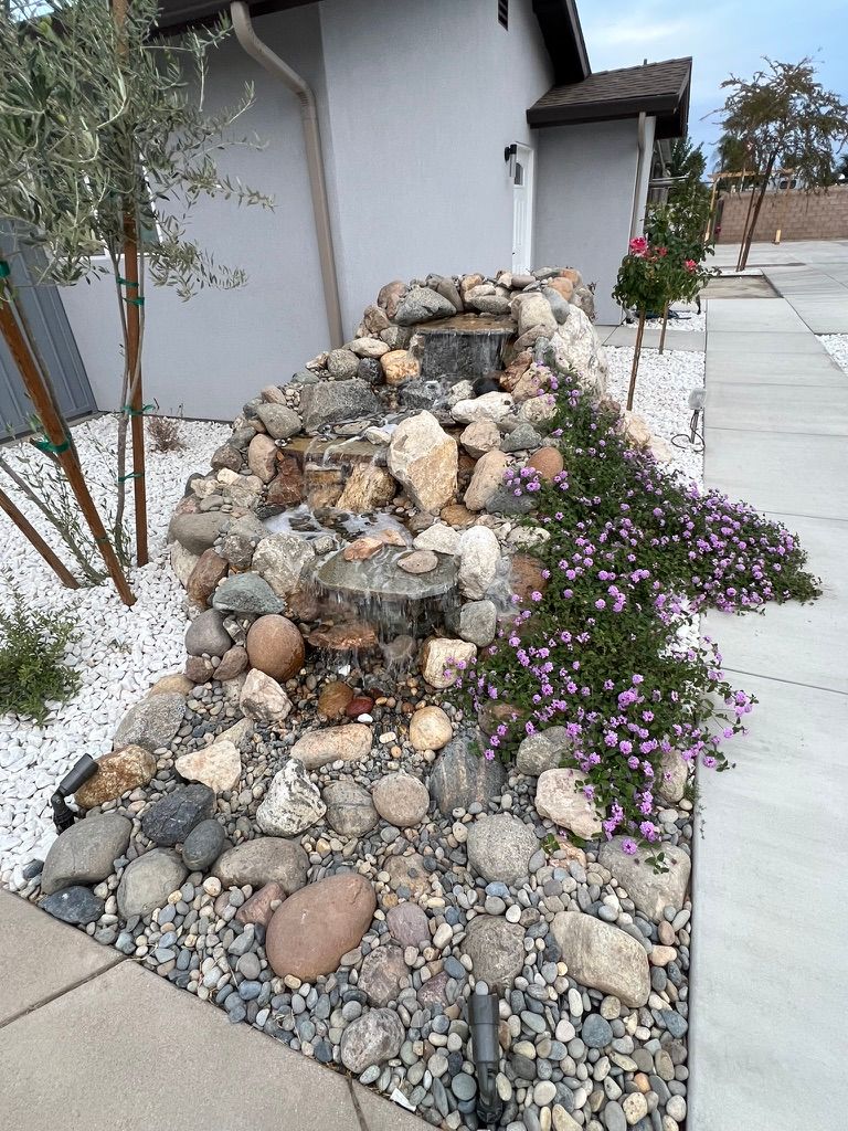 Natural rock waterfall feature with purple flowers