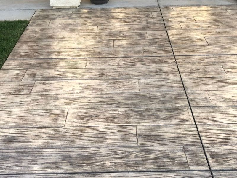 Stamped concrete walkway featuring detailed wood grain pattern with natural weathered wood coloring and texture