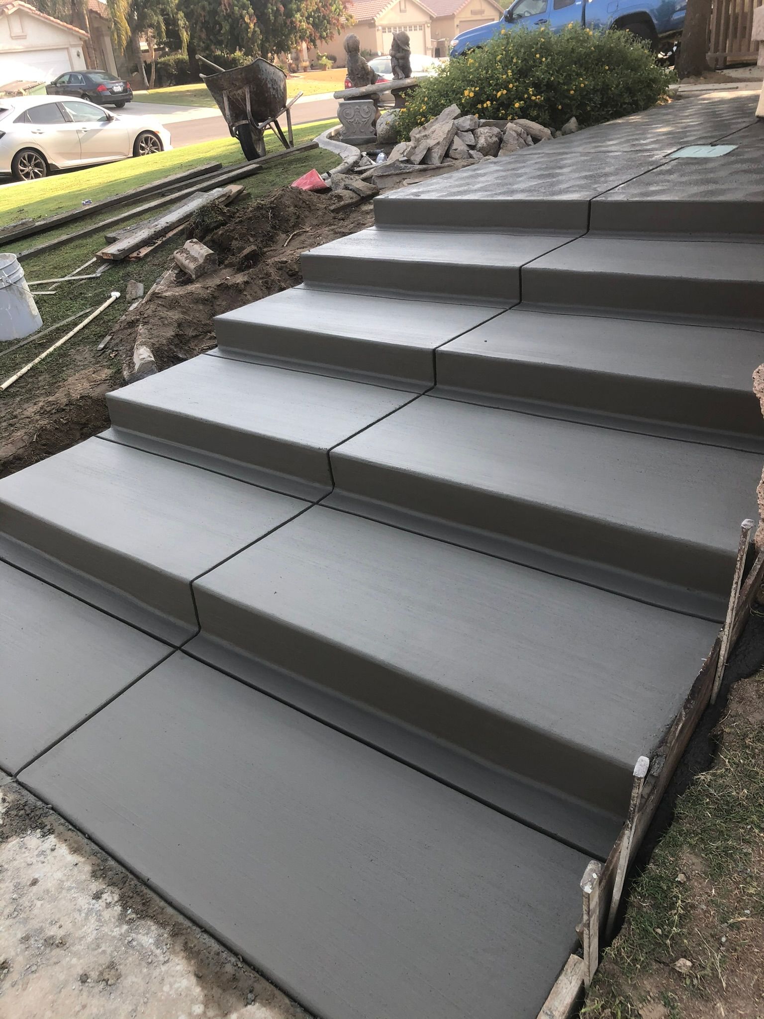 Newly poured concrete steps with clean edges and a smooth broom finish leading up to the front walkway.