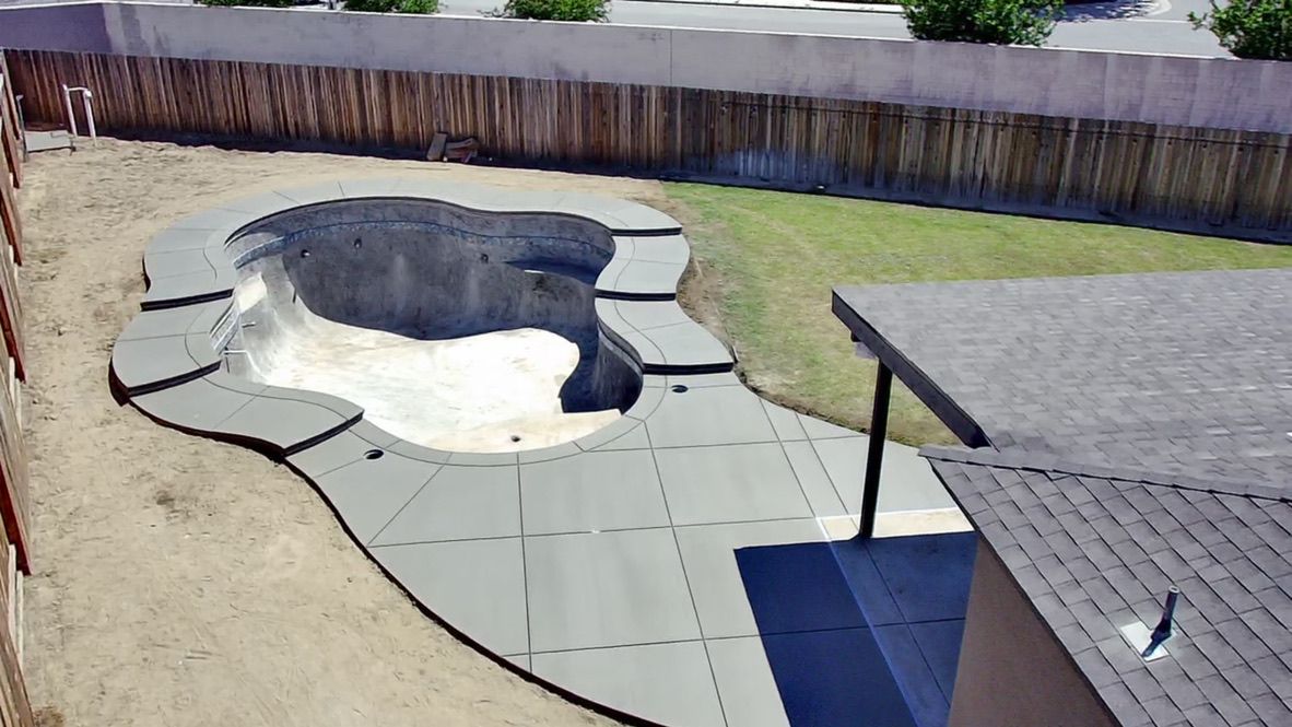 Custom gray concrete coping and smooth paver deck framing freeform pool