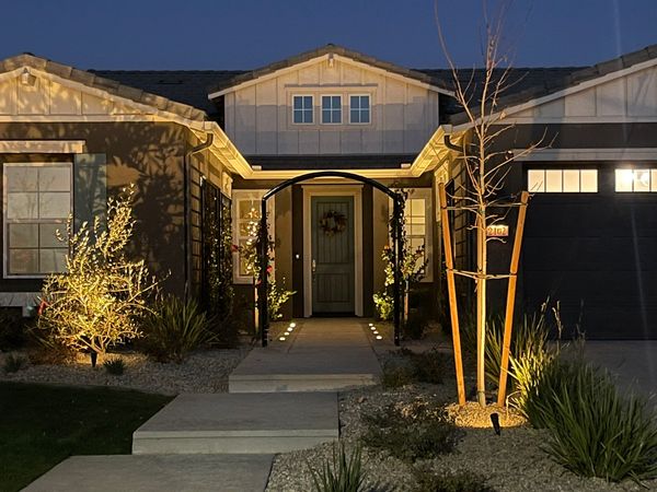 Front entry with iron arbor and landscape lighting at night