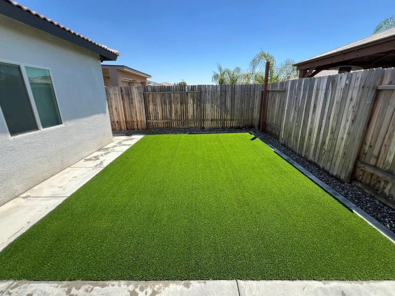 Backyard artificial turf with black rock border