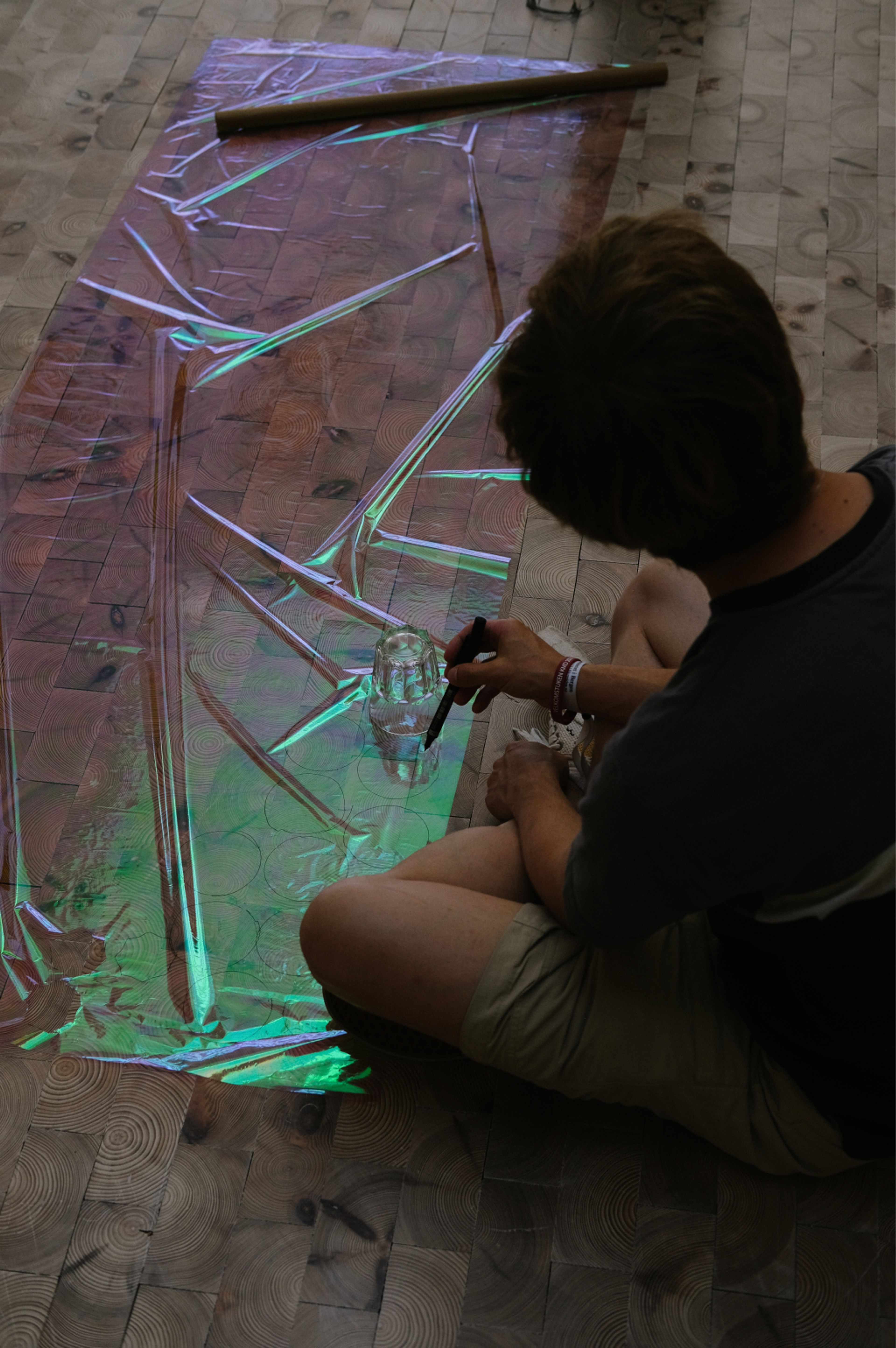 A gallery installation with a transparent purple-painted acrylic sculpture and a large four-panel abstract painting in purple and green brushstrokes.