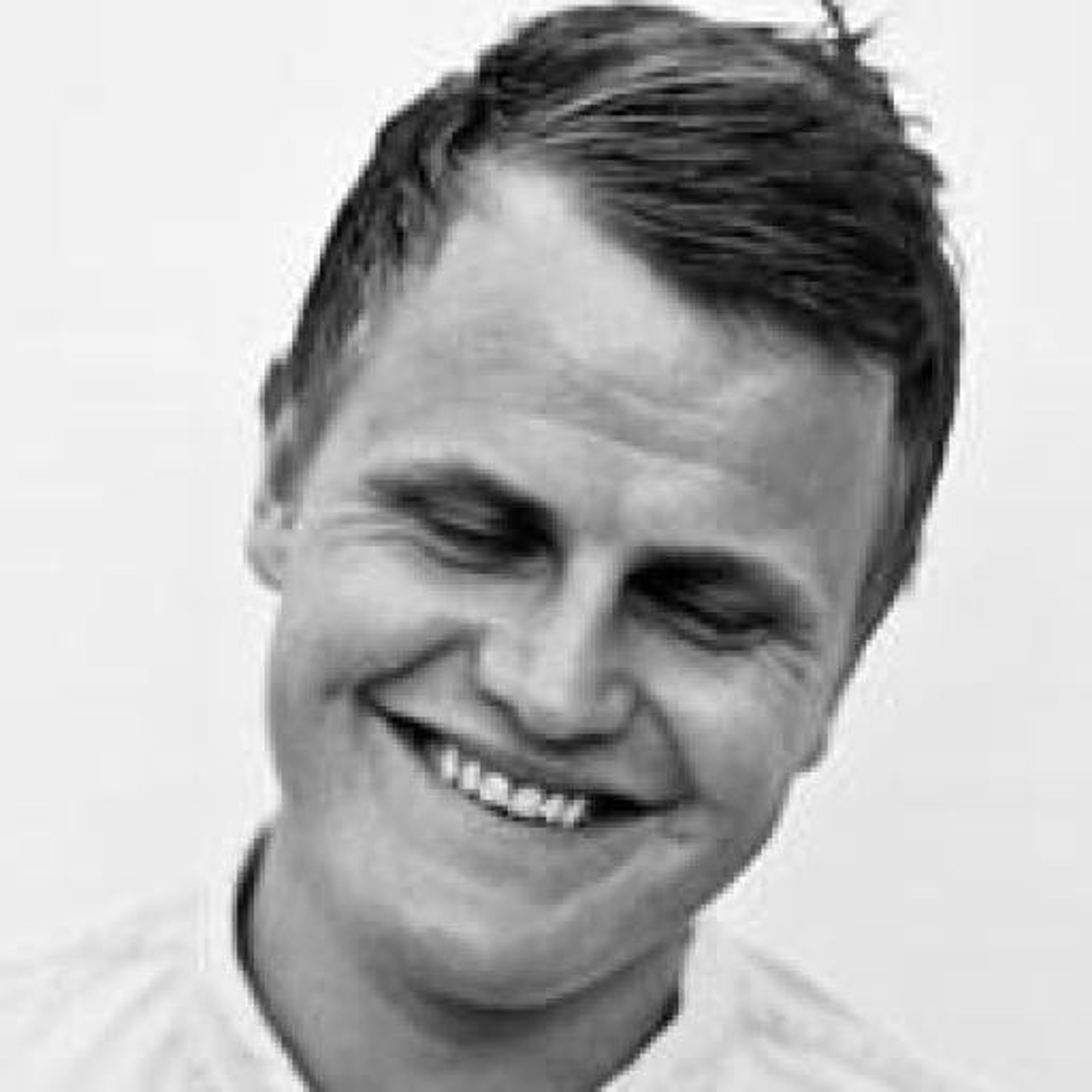 Black and white photo of a man smiling widely with his eyes closed.