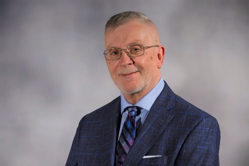 Dr. Terry D. Burger, a school psychologist with light hair and glasses, wearing a blue checkered suit and tie