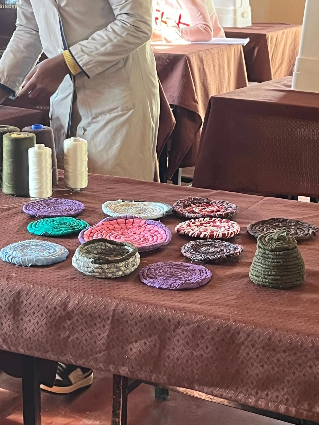 Pièces en chutes de tissus enroulées exposées sur une grande table ; plusieurs personnes dans la pièce.