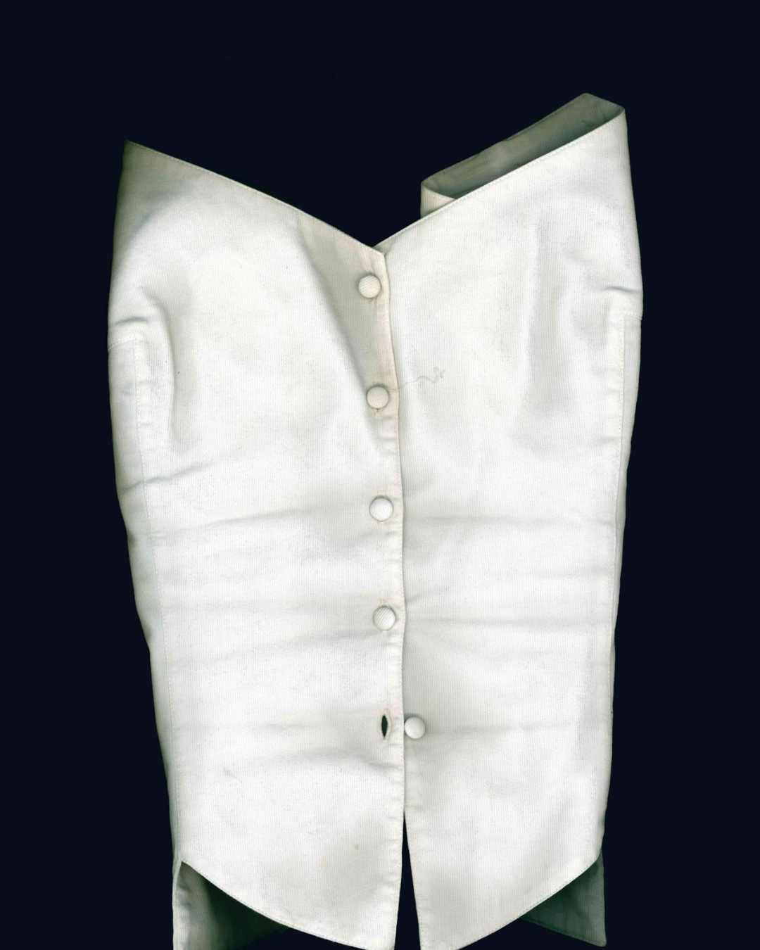 Gilet en tissu blanc cassé, boutonné, à coupe cintrée, sur fond noir.
