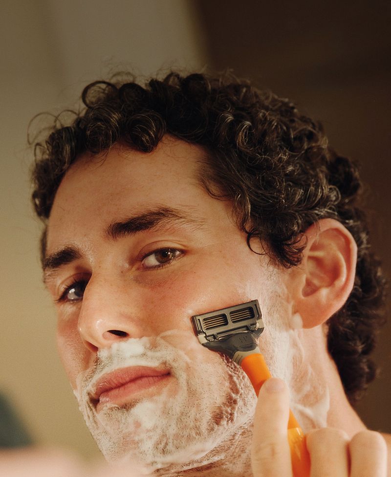Front of man's face showing him shaving against a blurry background