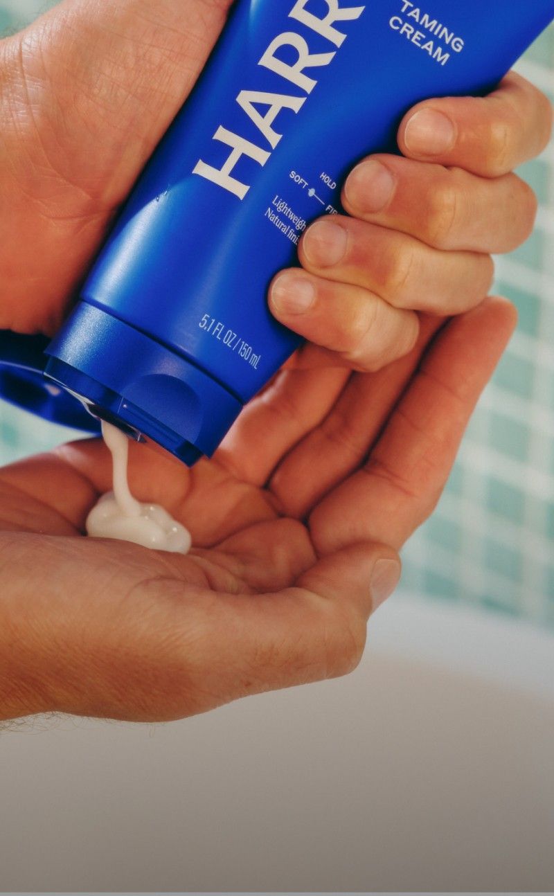 Blue container being squeezed to release product onto a hand.