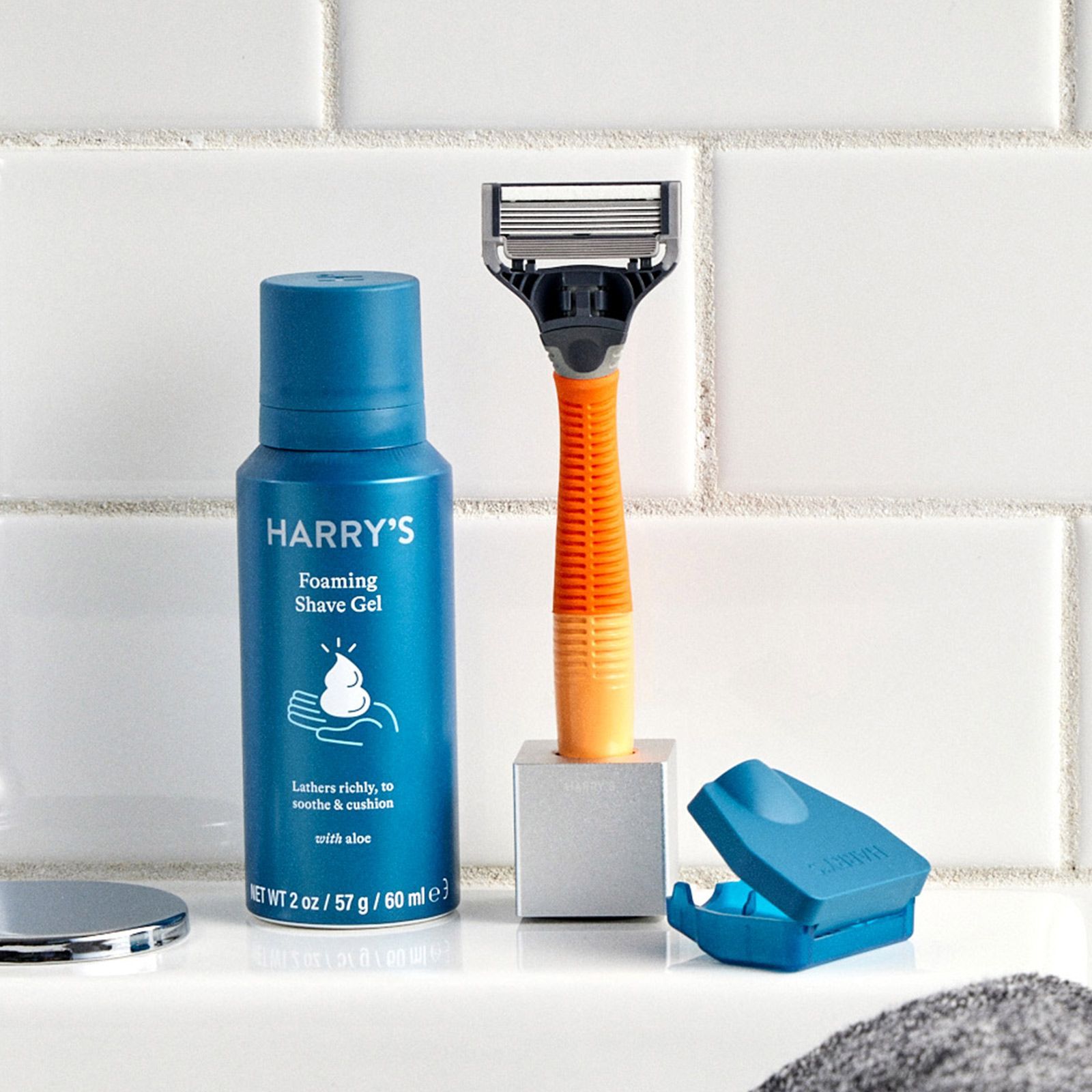 Mini Shave Gel and Ember Truman in the Razor Stand sitting on a white bathroom sink.